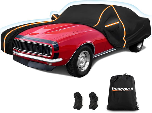A premium black car cover with orange reflective trim partially covering a red classic muscle car, shown with a BiGACOVER storage bag and two additional fastening straps.